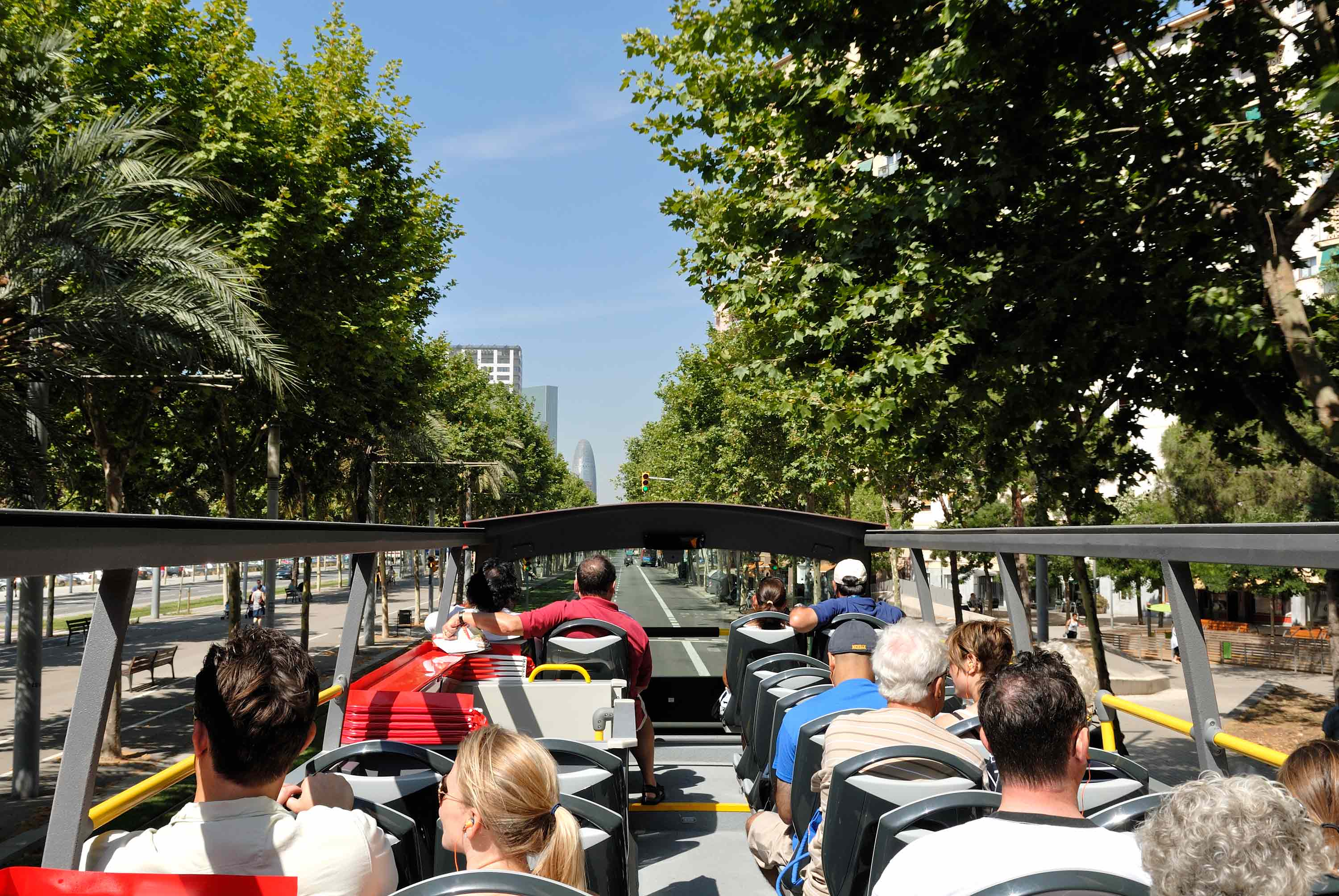 Top deck of the Barcelona City Tour red bus driving along a tree-lined Barcelona avenue